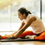 A person performing a self-stretch at home on a yoga mat